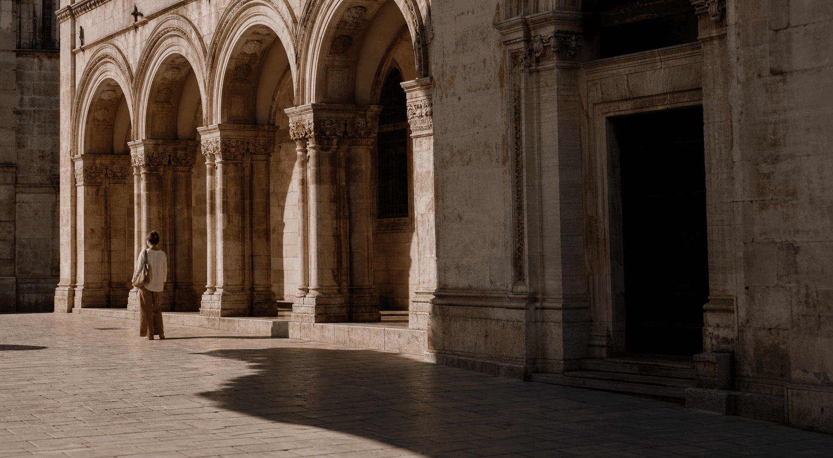 A traveler walking through a monumental stone arcade